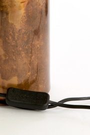 Detailaanzicht van de onderzijde van een cilindervormige lamp met bruin gemêleerde afwerking, zwart snoer en geïntegreerde snoerschakelaar, schuin van voren gefotografeerd