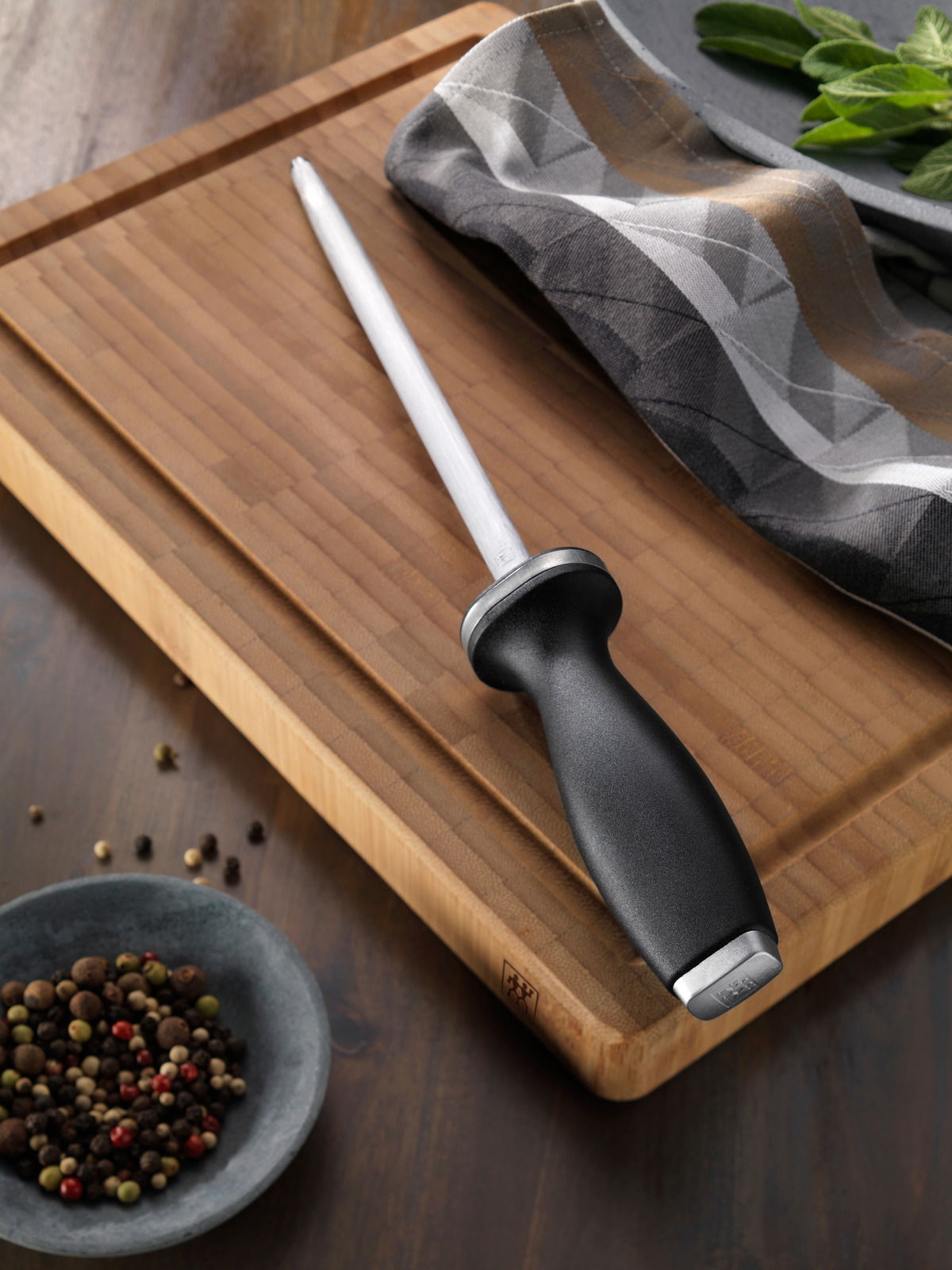 Wetzstahl mit Kunststoffgriff auf einem Holzbrett, seitliche Perspektive.