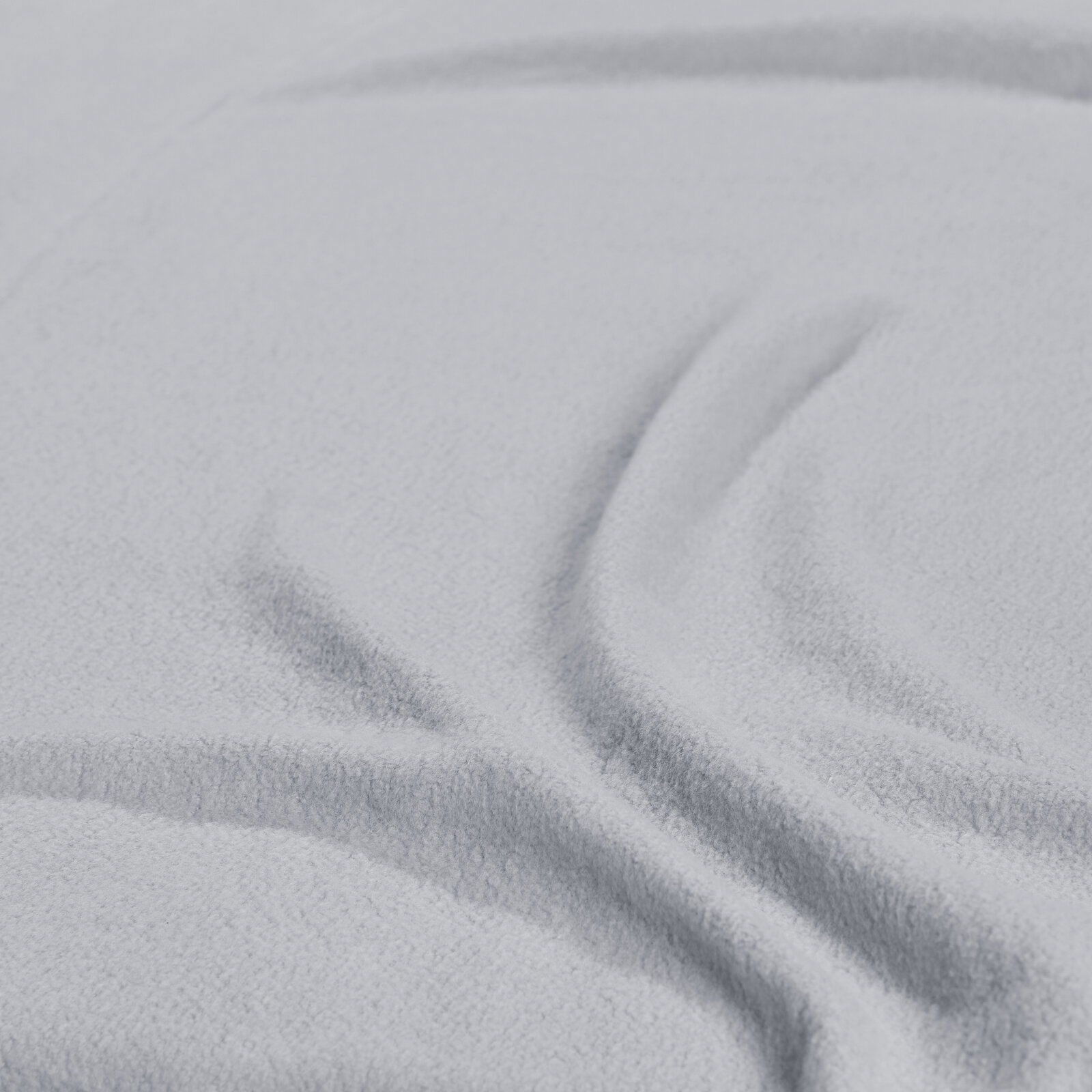 Nahaufnahme eines hellgrauen Spannbetttuchs mit weicher Textur und Falten.