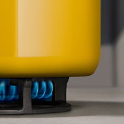 Gelber Topf auf einem Gasherd mit blauer Flamme, seitliche Perspektive