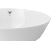 Nahaufnahme einer weißen Schale mit einem dezenten schwarzen Logo auf der Innenseite, seitliche Perspektive.
