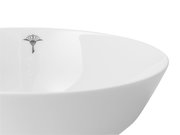 Nahaufnahme einer weißen Schale mit einem dezenten schwarzen Logo auf der Innenseite, seitliche Perspektive.
