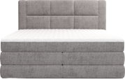 Grijs gestoffeerd boxspringbed met wit matras en gecapitonneerd hoofdbord, frontaal aanzicht