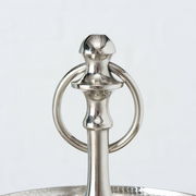 Nahaufnahme des oberen Teils einer silbernen Etagere mit einem dekorativen Griff und einem Ring, aus Aluminium gefertigt.