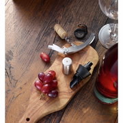 C&M-kelnermes op een houten plank met een wijnfles, een wijnglas en druiven, van bovenaf gefotografeerd.