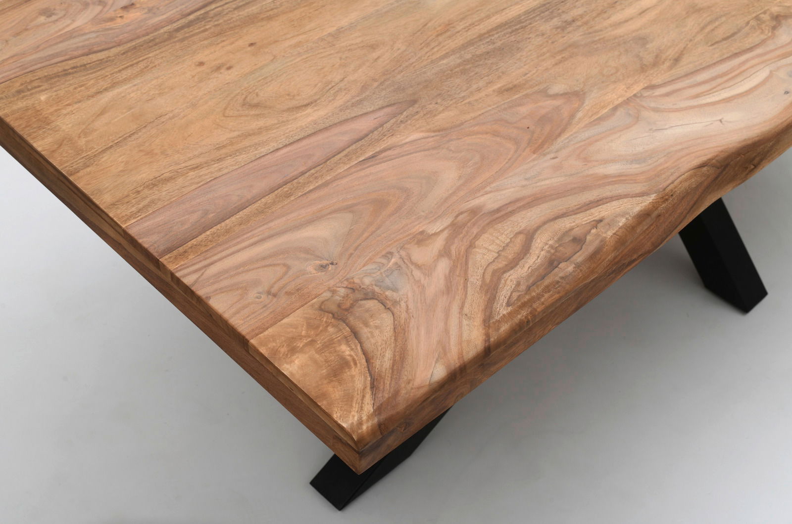 Nahaufnahme eines Esstisches aus Holz mit natürlicher Maserung und schwarzen Metallbeinen, aus der Vogelperspektive fotografiert.