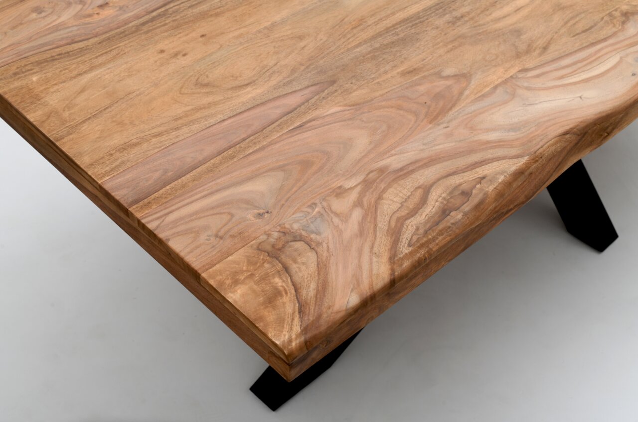 Nahaufnahme eines Esstisches aus Holz mit natürlicher Maserung und schwarzen Metallbeinen, aus der Vogelperspektive fotografiert.