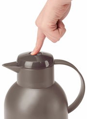 Nahaufnahme einer taupefarbenen Isolierkanne SAMBA 1,5L mit einem Finger, der den Deckelknopf drückt, seitliche Perspektive.