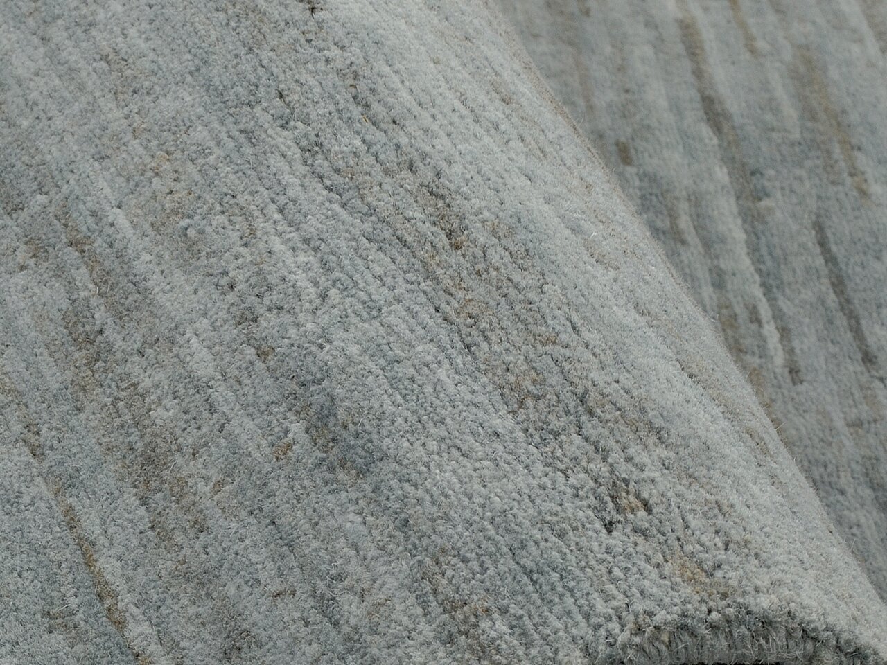 Nahaufnahme eines grauen Wollteppichs mit strukturierter Oberfläche.