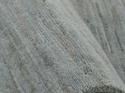 Nahaufnahme eines grauen Wollteppichs mit strukturierter Oberfläche.