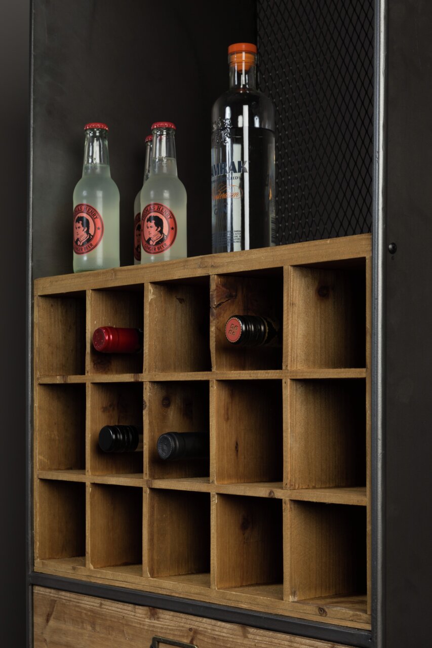 Nahaufnahme eines Weinregals aus Holz mit mehreren Fächern, in denen Weinflaschen horizontal gelagert sind. Oben stehen zwei Flaschen Ginger Beer und eine Flasche Gin. Perspektive von schräg vorne.