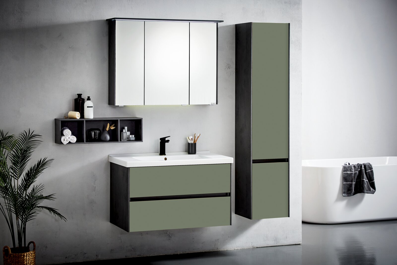 Modernes Badezimmermöbel-Set mit hängendem Waschtischunterschrank in Olivgrün mit schwarzem Korpus, weißem Waschbecken und schwarzer Armatur, dreitürigem Spiegelschrank, offenem Wandregal und hohem Seitenschrank; frontal aus leichter Seitenperspektive auf