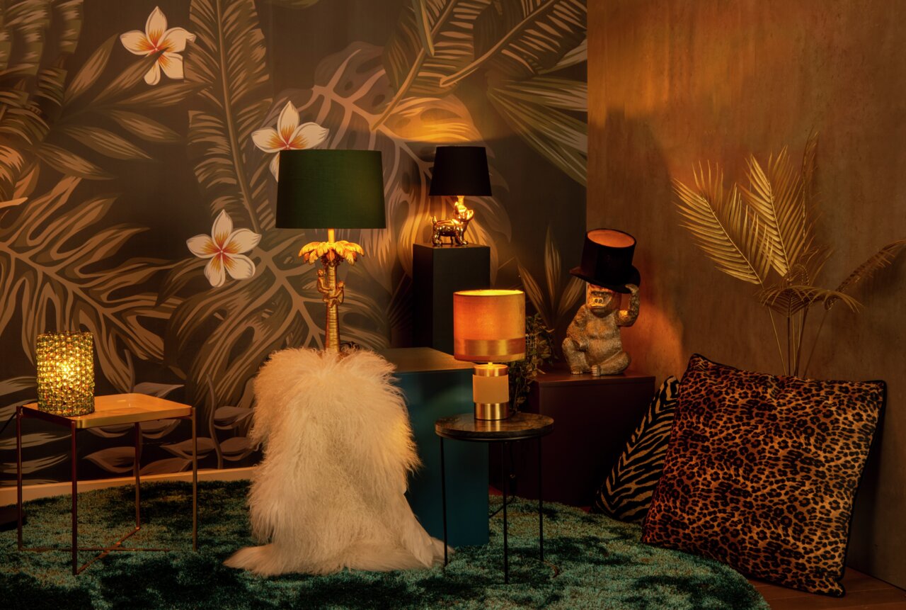 Sfeervolle interieurfoto met de tafellamp COCONUT op de voorgrond, omringd door exotische decoraties en warm licht.