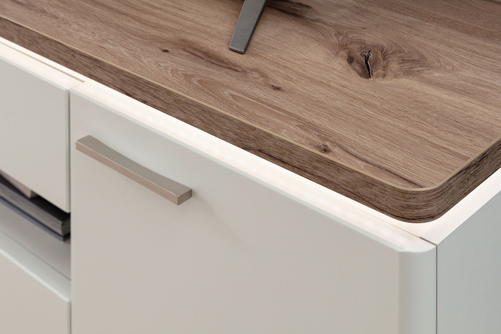Nahaufnahme einer modernen weißen Kommode mit Holzoberfläche und LED-Beleuchtung, seitliche Perspektive.