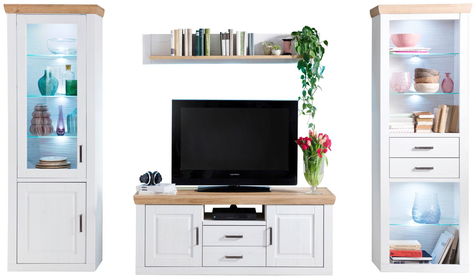 Frontale Ansicht einer modernen Wandkombination in Weiß mit Holzdetails, bestehend aus zwei Vitrinen, einem TV-Schrank und einem Wandregal, dekoriert mit Büchern, Pflanzen und Geschirr.