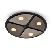 Runde schwarze Deckenleuchte mit vier warmweiß leuchtenden Spots und segmentierter Rauchglas-Optik, aus schräger Untersicht vor weißem Hintergrund
