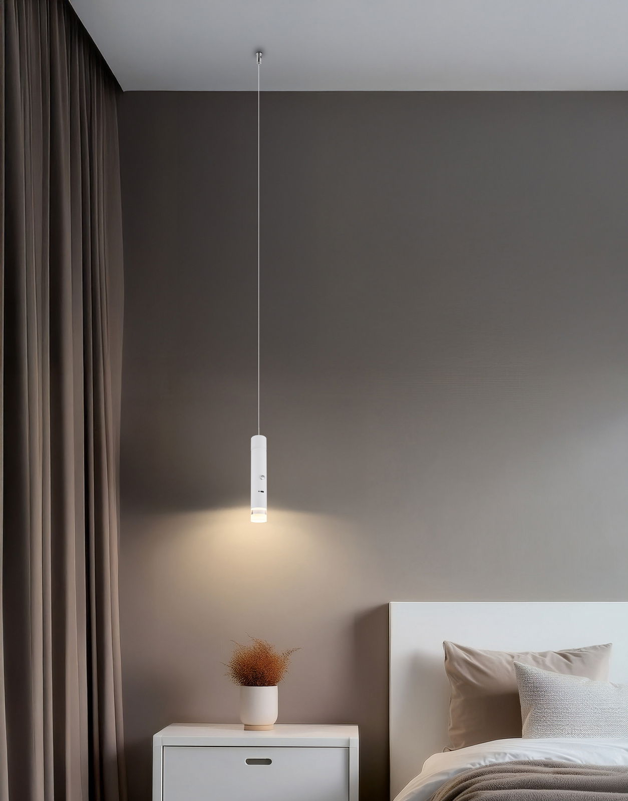 Moderne Akku-Pendelleuchte in einem Schlafzimmer, von der Seite betrachtet, mit warmem Licht über einem Nachttisch.