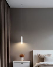 Moderne Akku-Pendelleuchte in einem Schlafzimmer, von der Seite betrachtet, mit warmem Licht über einem Nachttisch.