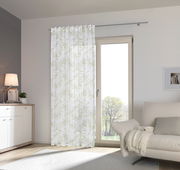 Fertigvorhang Flora 140x245 mit zartem Blattmuster, aufgehängt vor einer Terrassentür in einem modernen Wohnzimmer, seitliche Perspektive