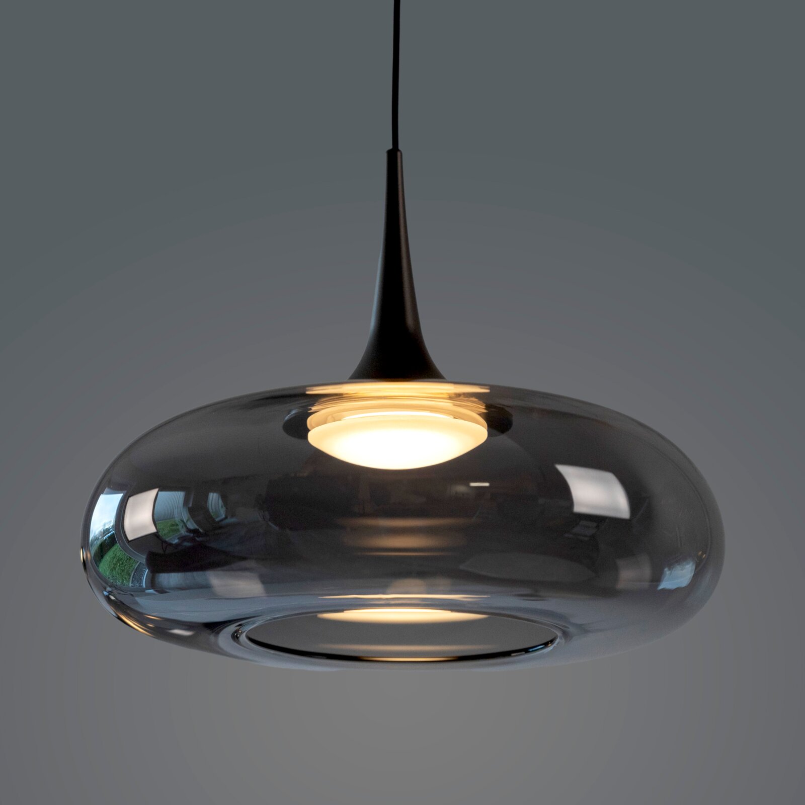 Moderne schwarze Pendelleuchte mit rauchgrauem, glänzendem Glas-Schirm und warmem Licht, Nahaufnahme in leichter Untersicht von unten