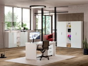Modernes Büro mit weißem Schreibtisch, Rollcontainer und Aktenschränken, seitliche Perspektive
