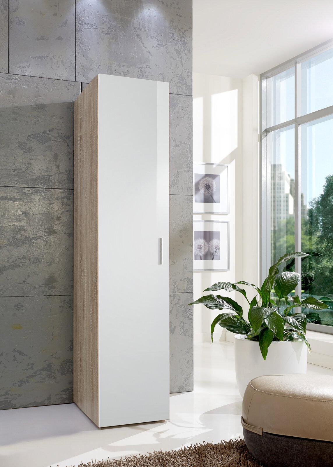 Moderner, schmaler Kleiderschrank in Holzoptik mit weißer Tür, seitliche Perspektive, in einem hellen Raum mit großen Fenstern und Pflanzen.