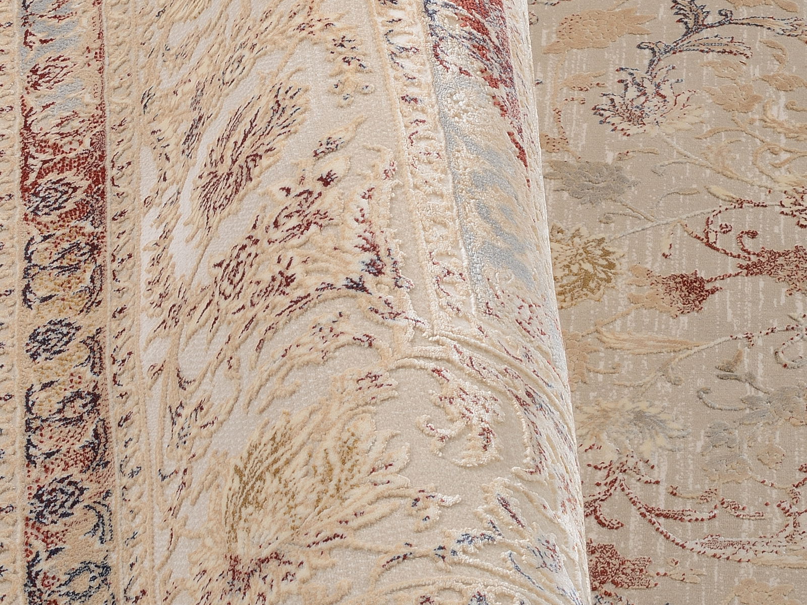 Nahaufnahme eines Orientteppichs mit floralen Mustern in Beige-, Rot- und Blautönen, seitliche Perspektive