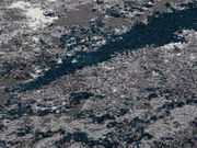 Nahaufnahme eines flauschigen Teppichs in Grautönen mit blauen Akzenten, perspektivisch von oben betrachtet.