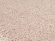 Nahaufnahme eines weichen, cremefarbenen Teppichs mit flauschiger Textur, von oben betrachtet.