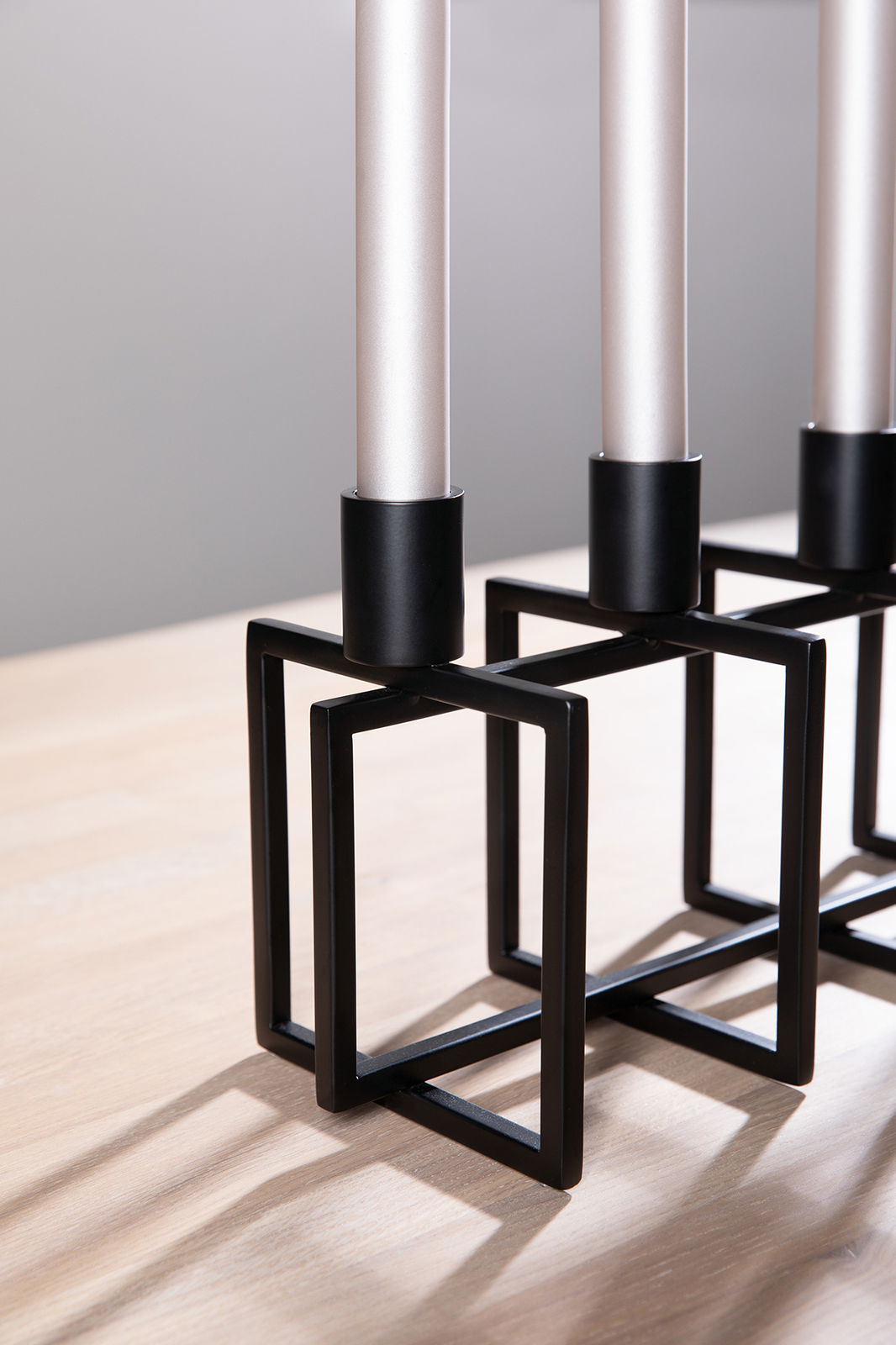 Moderner 4-flammiger Leuchter mit schwarzem geometrischem Metallgestell, seitliche Perspektive.