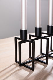 Moderner 4-flammiger Leuchter mit schwarzem geometrischem Metallgestell, seitliche Perspektive.