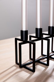 Moderner 4-flammiger Leuchter mit schwarzem geometrischem Metallgestell, seitliche Perspektive.