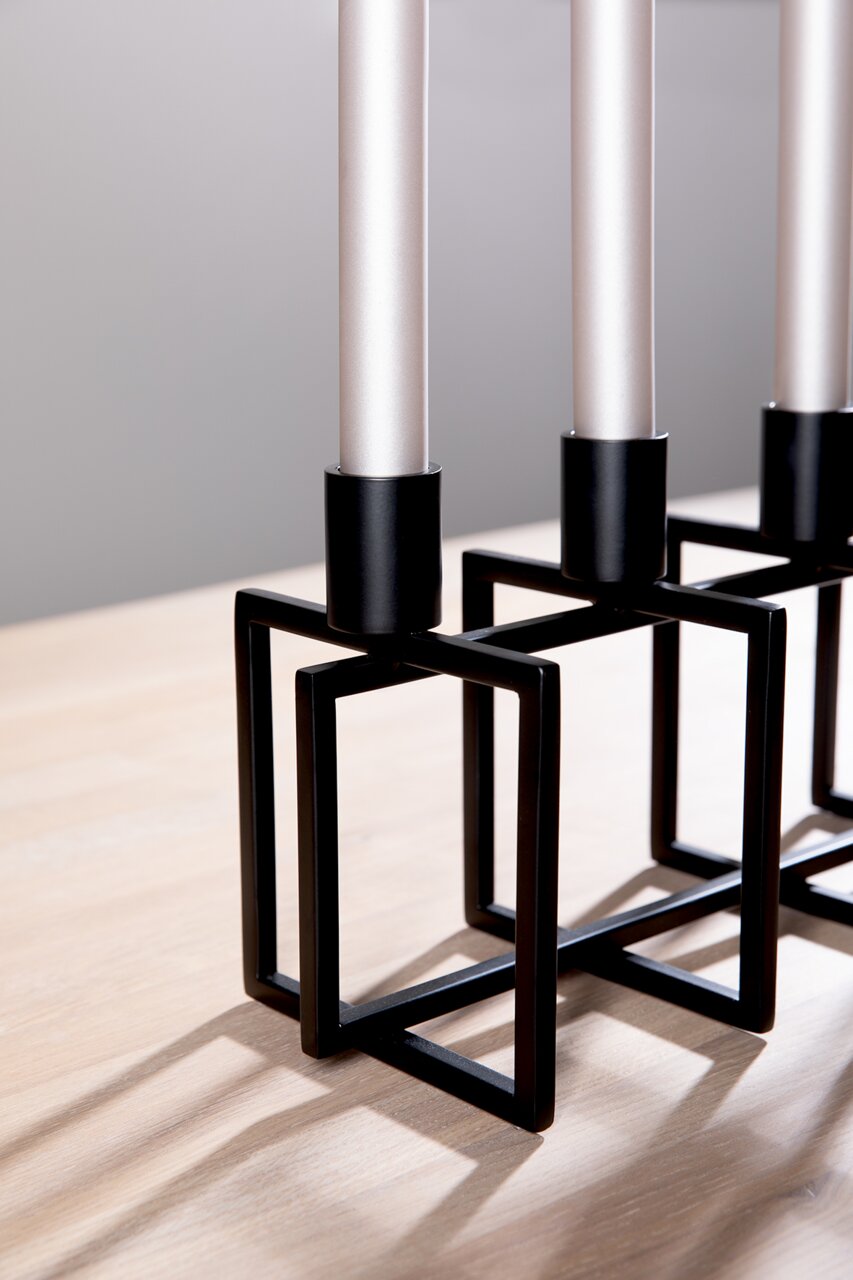 Moderne vierarmige kandelaar met een zwart, geometrisch metalen frame, gezien vanaf de zijkant.