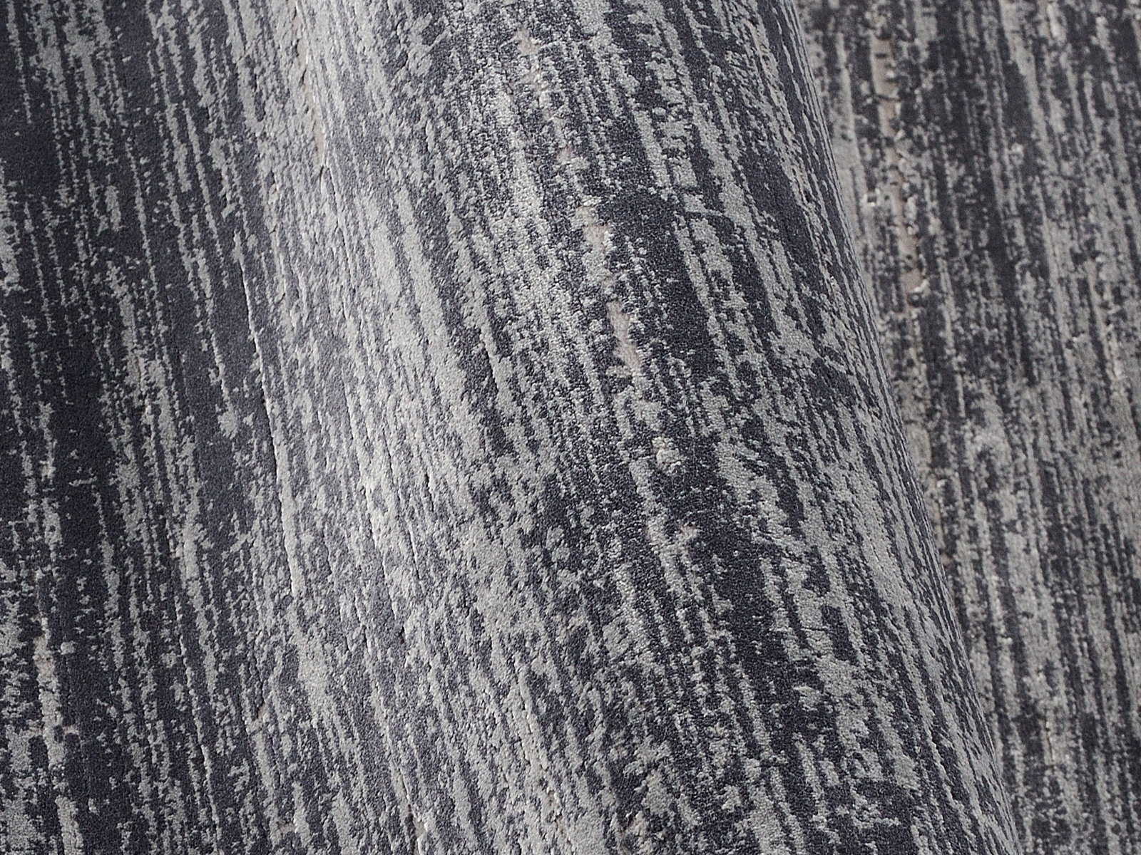 Nahaufnahme eines Designer Teppichs mit grauem und schwarzem Muster in diagonaler Perspektive