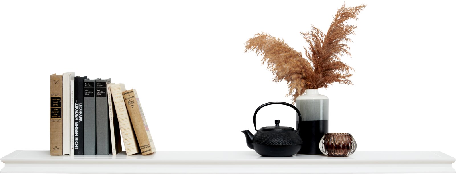 Wandboard ALICE 120cm in Weiß, dekoriert mit Büchern, einer schwarzen Teekanne, einer Vase mit getrockneten Gräsern und einem kleinen Teelichthalter, seitliche Perspektive.