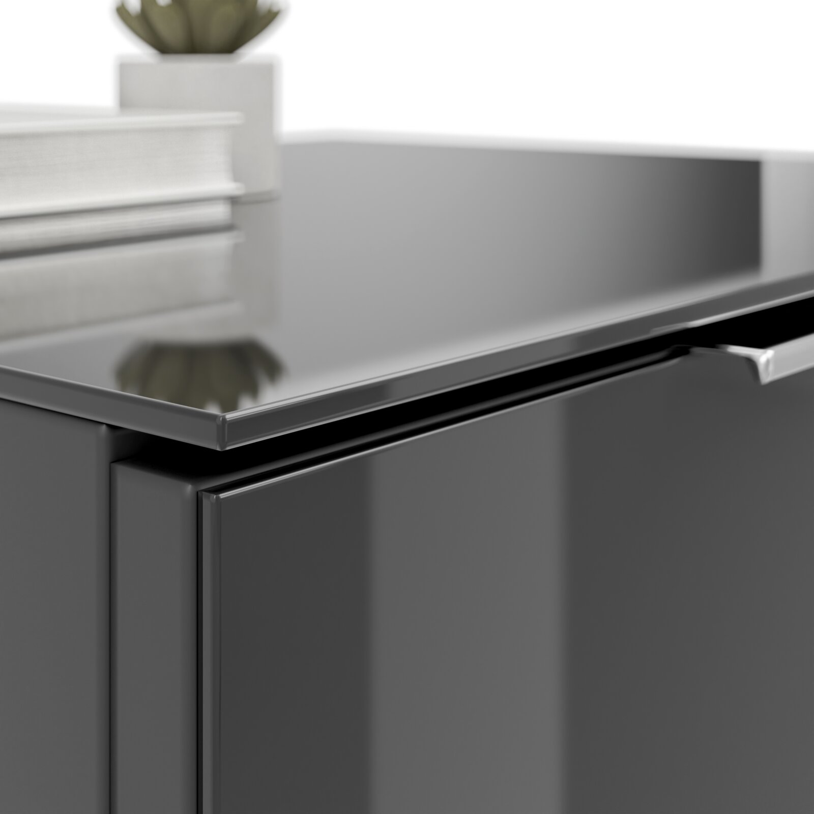 Nahaufnahme einer modernen, glänzenden Nachtkommode in dunkler Farbe mit einem Buch und einer Pflanze darauf.