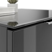 Nahaufnahme einer modernen, glänzenden Nachtkommode in dunkler Farbe mit einem Buch und einer Pflanze darauf.