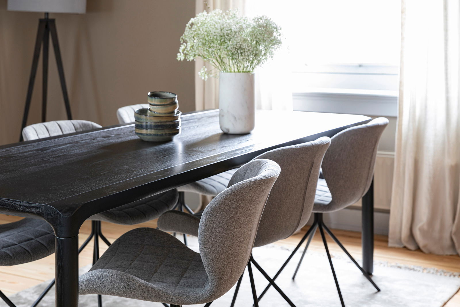 Esszimmer mit modernem schwarzen Tisch und vier grauen Stühlen, seitliche Perspektive