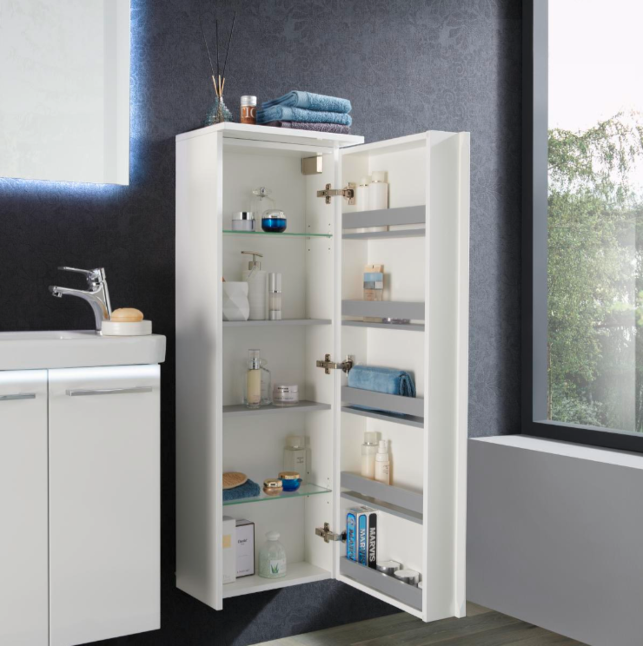 Voleo Kofferschrank rechts LARA Moderner weißer Kofferschrank rechts, geöffnet, mit mehreren Regalen und Pflegeprodukten, seitliche Perspektive