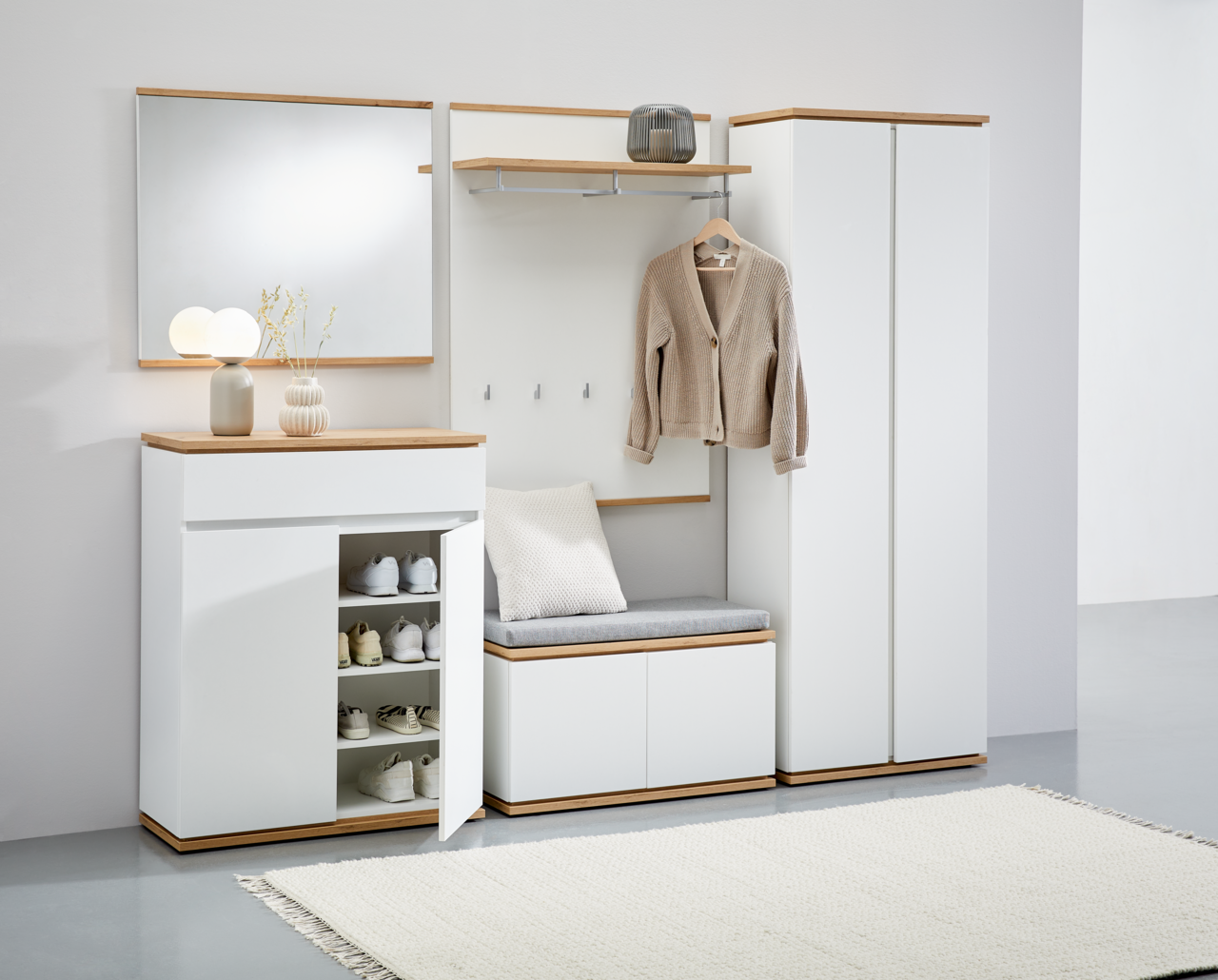 XORA Garderobenpaneel YAMAEL Moderne Garderobenkombination in Weiß mit Holzdetails, bestehend aus Schuhschrank, Spiegel, Garderobenbank und Garderobenschrank, frontal abgebildet.