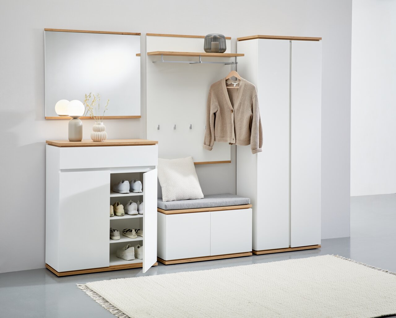 XORA Garderobenbank YAMAEL Moderne Garderobenkombination in Weiß mit Holzdetails, bestehend aus Schuhschrank, Spiegel, Garderobenbank und Garderobenschrank, frontal abgebildet.