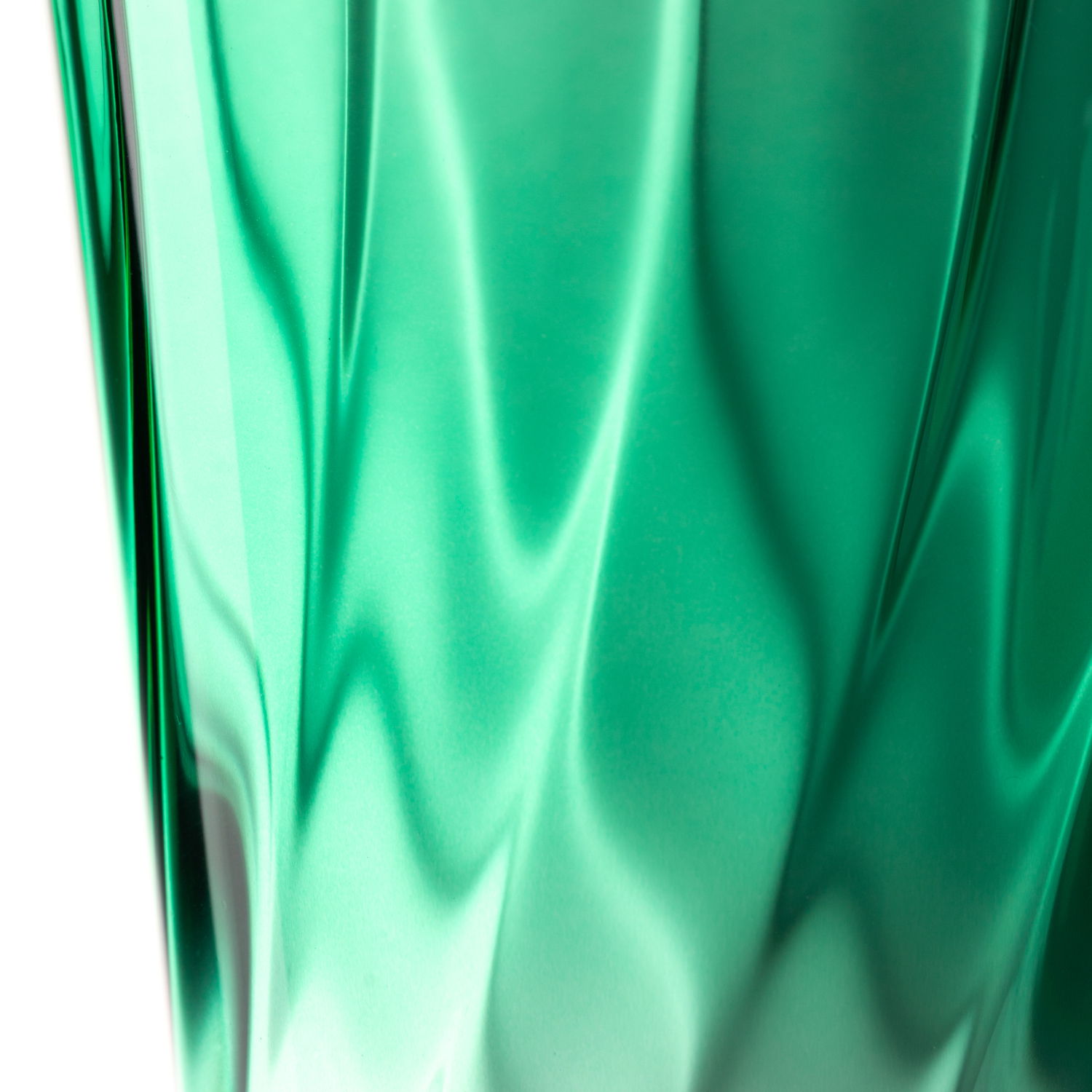 Nahaufnahme eines grünen Trinkglases mit verdrehtem Design, seitliche Perspektive