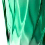 Nahaufnahme eines grünen Trinkglases mit verdrehtem Design, seitliche Perspektive