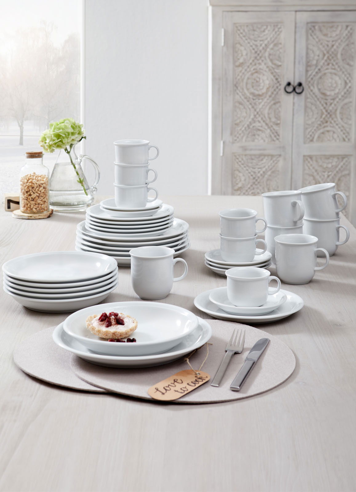 Kombiservice Trend weiß 30-tlg, bestehend aus Tellern, Tassen und Schalen, auf einem Tisch arrangiert, seitliche Perspektive.