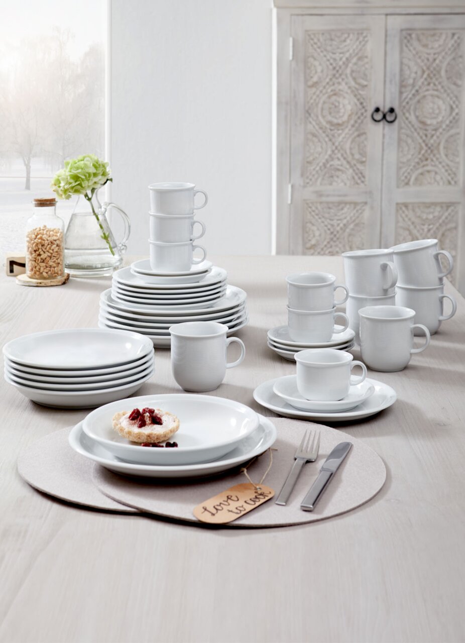 Kombiservice Trend weiß 30-tlg, bestehend aus Tellern, Tassen und Schalen, auf einem Tisch arrangiert, seitliche Perspektive.