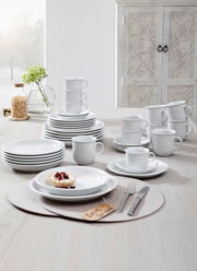 Kombiservice Trend weiß 30-tlg, bestehend aus Tellern, Tassen und Schalen, auf einem Tisch arrangiert, seitliche Perspektive.