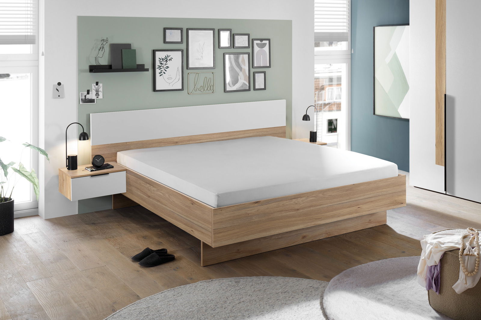 Modernes Schlafzimmer mit einem stilvollen Holzbett, flankiert von zwei Nachttischen mit Lampen. Die Wand ist mit Kunstwerken dekoriert. Perspektive: seitliche Ansicht des Bettes.