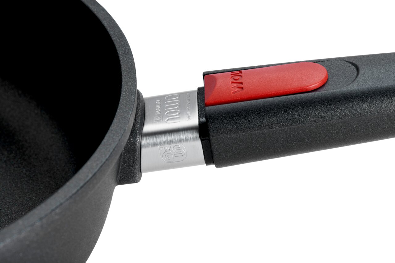 Close-up van een Nowo-pan met hoge rand van 28 cm, met een rode knop aan het handvat, gezien vanaf de zijkant.