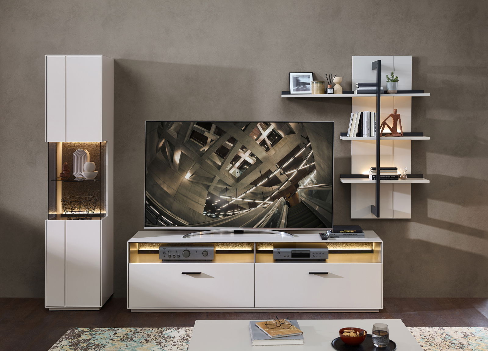 Moderne Wandkombination COMO von Zurbrüggen in Weiß mit integriertem TV-Schrank, Regalen und dekorativer Beleuchtung, frontal betrachtet.