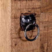 Close-up van een rustiek houten secretaire met een antieke metalen ringgreep, gezien vanaf de zijkant.